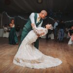 man in black suit jacket holding woman in white wedding dress